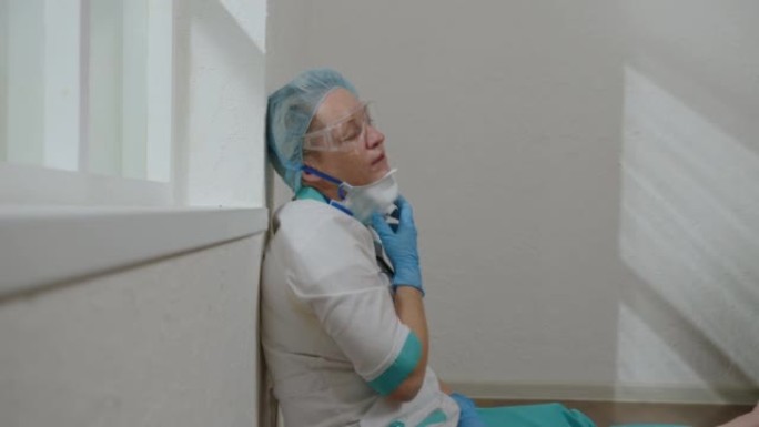 疲惫的外科医生坐在医院窗户附近的地板上，过度劳累