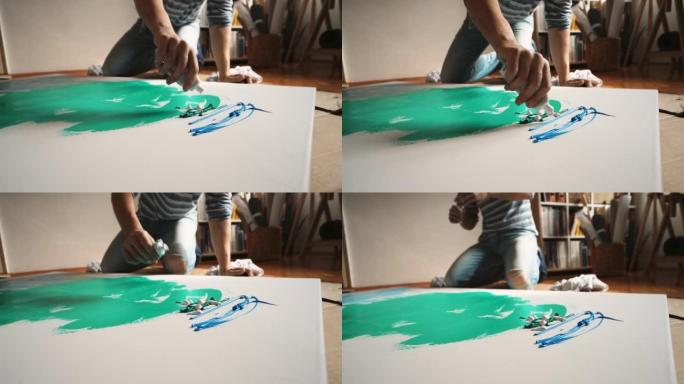 高加索男性艺术家从画布上的油漆管中挤压油漆
