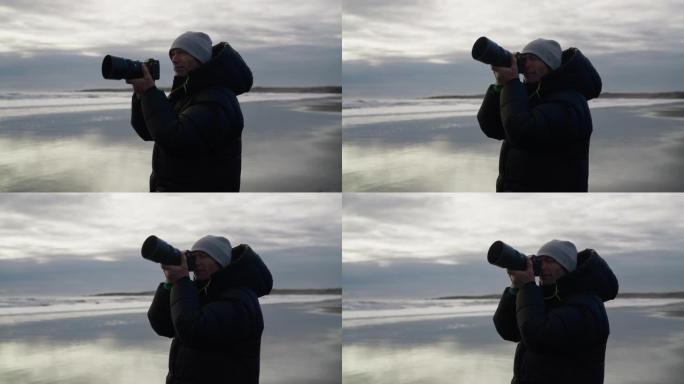 摄影师举起相机在潮湿的海滩上拍摄