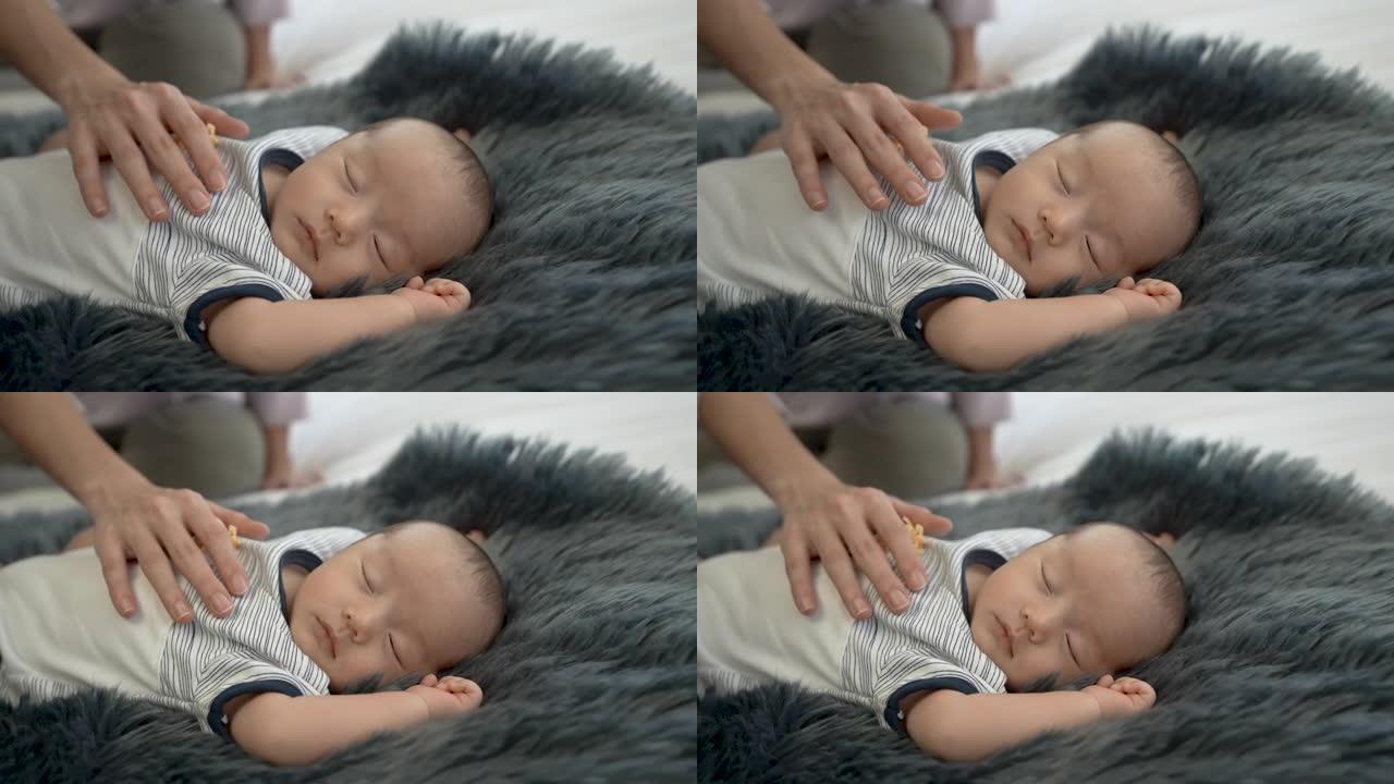 4K 50fps，近距离新生儿，2个月大，亚洲人睡在黑灰色的地毯上，母亲的手放在胸前，使婴儿睡得很好