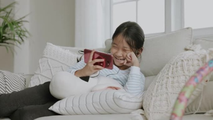 女孩在妈妈智能手机上看卡通片，在家靠电子学习后打破时间。