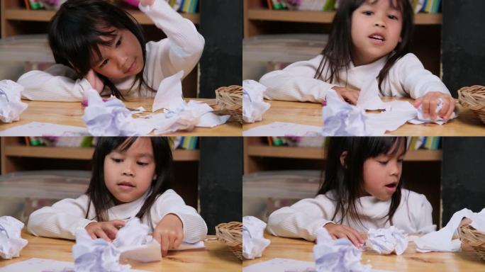心烦意乱的小女孩在家里画了一幅五颜六色的画，把桌子上的纸弄皱了。在冠状病毒大流行期间厌倦在线学习和家