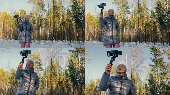冬季手持薄膜三轴万向节稳定装置的女人为智能手机。摄像师操作员拍摄照片视频
