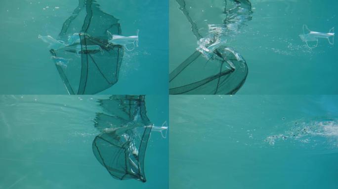 医用口罩在蓝色水柱水下漂移。Net从水中去除口罩，清洁环境并消除对自然的威胁。海洋中的污染问题概念。