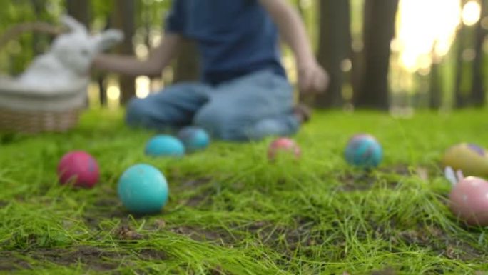 复活节那天，小男孩在春天的花园里寻找鸡蛋。传统的户外复活节节日。关注多色鸡蛋。