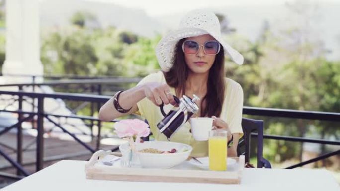 4k视频片段，一位迷人的年轻女子在度假时坐下来在外面吃早餐
