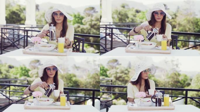 4k视频片段，一位迷人的年轻女子在度假时坐下来在外面吃早餐
