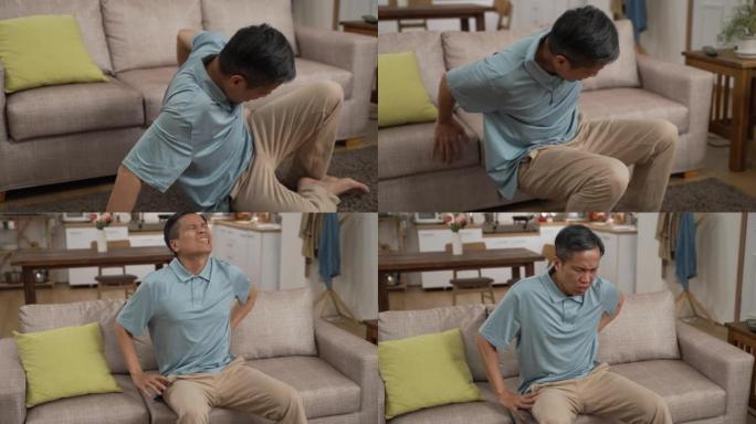 中国成熟男子移动坐在沙发上休息，同时下背部疼痛，呻吟着非常不适。老年人滑倒和跌倒风险的概念