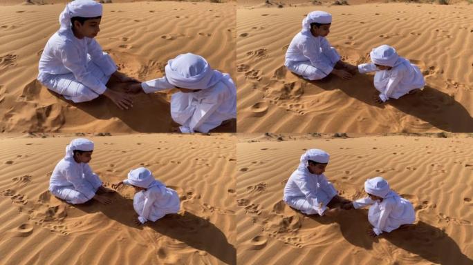 两个Emarati孩子在沙漠中玩沙子