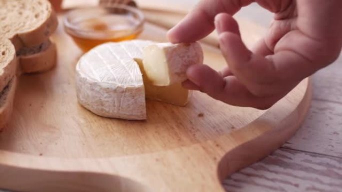 手的特写从砧板上摘下一片奶酪