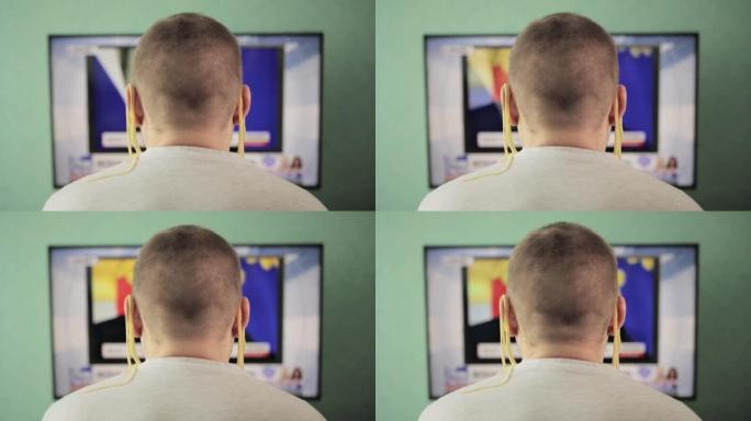 一个耳朵上挂着面条的男人在看电视。互联网上的欺骗和假货的概念。未经证实的信息，新闻频道