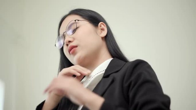 办公室综合症的概念，亚洲女商人在计算机上工作，她经历颈部疼痛，用一只手触摸他的脖子，转头试图减轻疼痛
