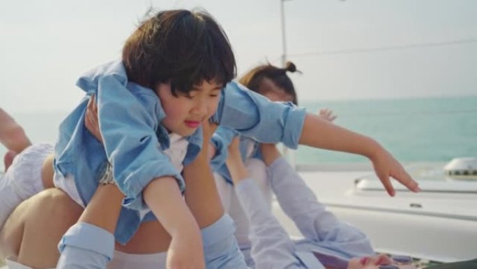 有两个孩子的亚洲家庭在游艇上玩得很开心。