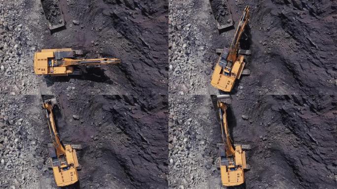 黄矿挖掘机的无人机视图在露天煤矿区将煤炭装载到大型自卸车中。采石场采煤过程的航拍画面。