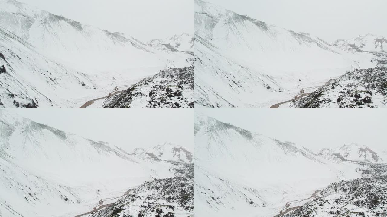 无人机在积雪覆盖的山脉上，下面是辫状河