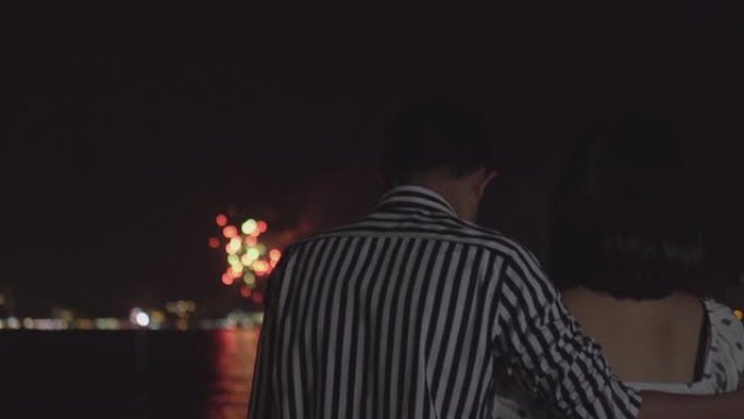 快乐的年轻亚洲夫妇晚上在海滩上享受烟花汇演