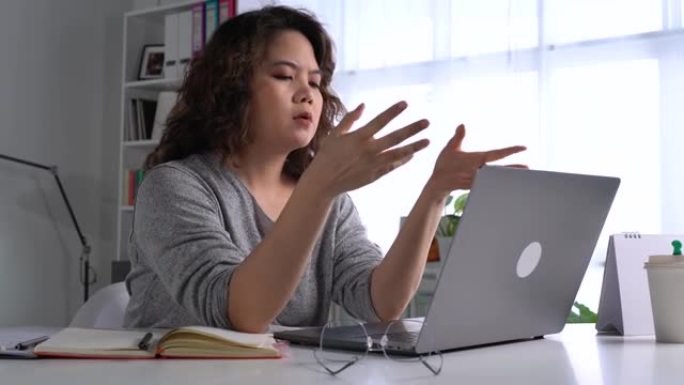 感到疲倦和压力。年轻的亚洲妇女坐在办公室里用笔记本电脑工作时，思想深处疲惫不堪。