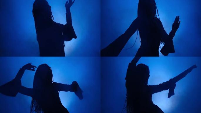 在蓝色灯光和烟雾中跳舞的女人的剪影