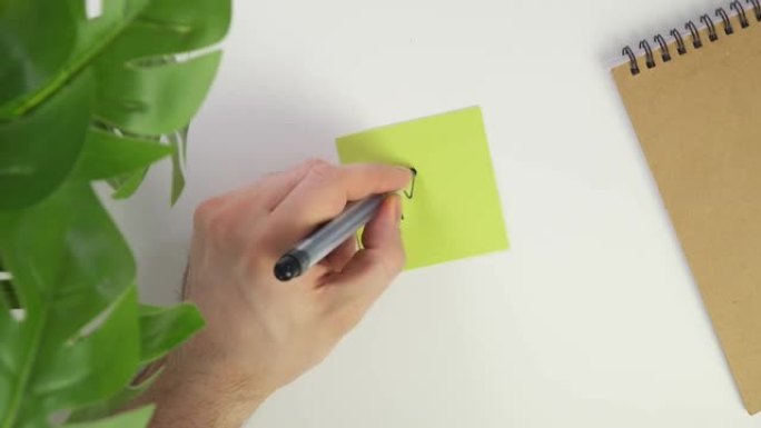 俯视图用笔在贴纸上写OMG。在办公桌上放一张彩色的纸，然后用黑色记号笔写一张便条。