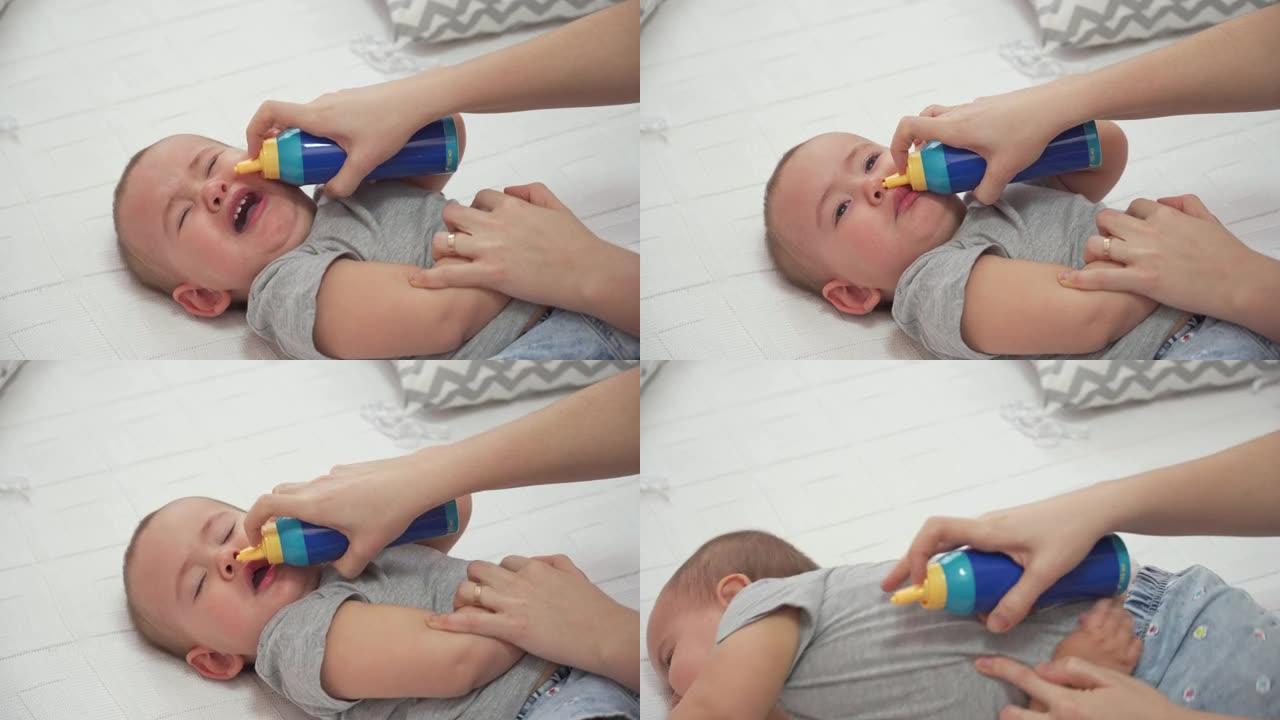 妈妈在哭泣的12-17个月大的婴儿的鼻子中使用带有海水的鼻喷剂