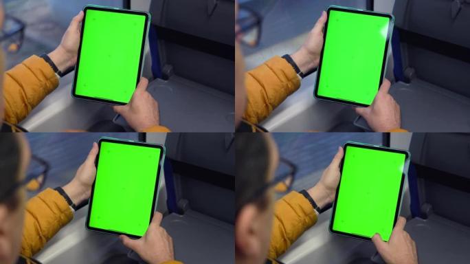 绿屏和火车在线浏览的man watch平板电脑的后视图。模拟观看pad上的内容。坐在公共交通工具室内
