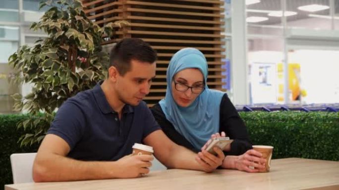 穆斯林女孩和年轻人在咖啡馆里聊天很开心，特写