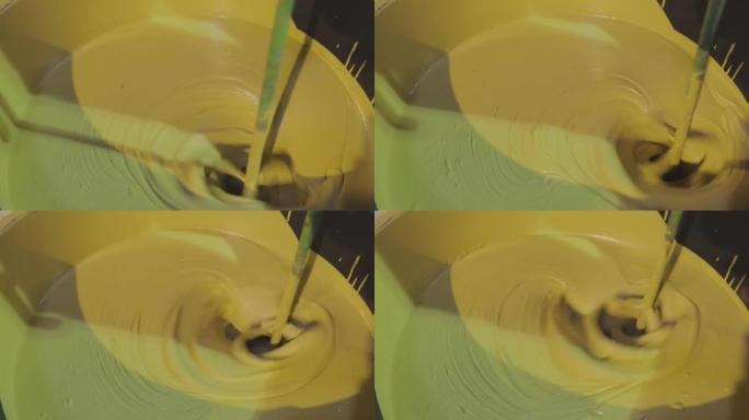 在桶里搅拌油漆。在桶中搅拌黄色油漆的特写镜头