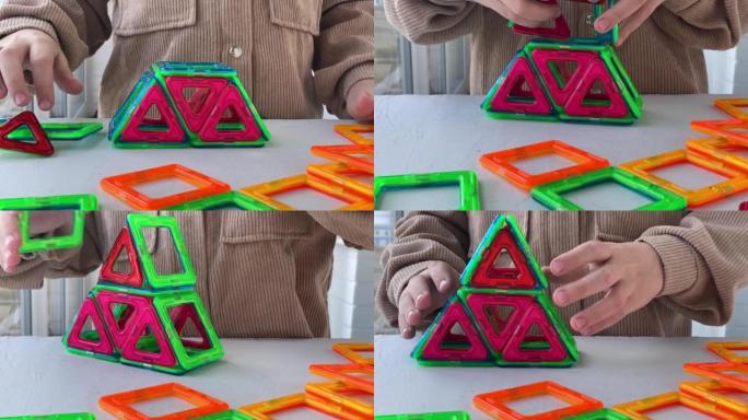 一个孩子玩彩色积木的特写镜头，这个孩子从一个磁性积木制作了一个人物。