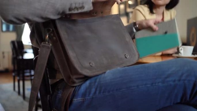 B-商人在咖啡店与同事会面时，从皮革公文包中拿出笔记本电脑