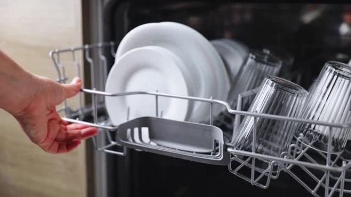 打开的厨房洗碗机的女性手动插入和装载篮