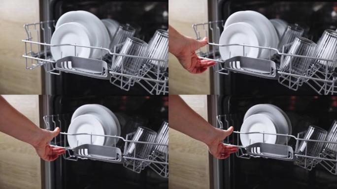打开的厨房洗碗机的女性手动插入和装载篮