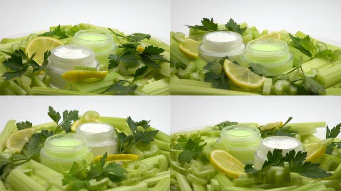 装有柠檬和芹菜护肤品的罐子放在一堆新鲜的芹菜茎和柠檬片上。