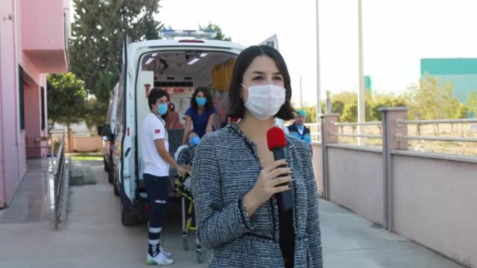戴着口罩的新闻播音员报道大流行期间医院前的突发新闻