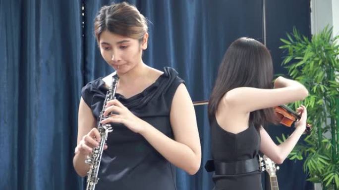 十几岁的女孩音乐家穿着黑衣服演奏长笛、双簧管和小提琴。