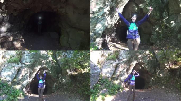 背着背包，额头上打着手电筒的女孩游客从黑暗的洞穴中跑出来，喜欢举起双手。获胜者的概念