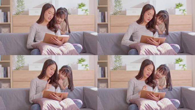 一位亚洲妈妈和她的孩子正在一起读书。妈妈在教孩子。孩子专心妈妈。妈妈坐在沙发上，女儿站在沙发后面。妈
