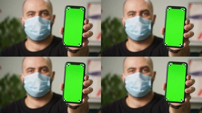 男子戴着医用口罩，显示带色度绿屏的手机，带二维码的疫苗接种护照，移动设备上的国际冠状病毒covid 