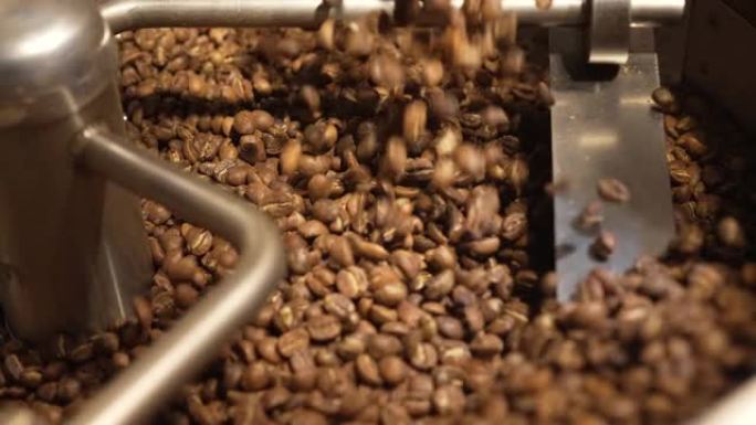 将罗布斯塔或阿拉比卡咖啡豆倒入工业焙烧炉中。咖啡豆被倒入并旋转。工业焙烧。混合咖啡粒。咖啡馆的背景。
