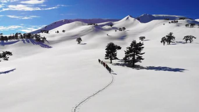 高山登山队在冬季高海拔山峰中连续行走的高空俯视图