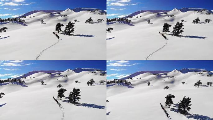高山登山队在冬季高海拔山峰中连续行走的高空俯视图