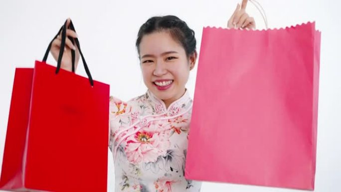 中国/亚洲妇女在农历新年期间，穿着红色的购物袋，在白色背景上，穿着旗袍白色碎花图案连衣裙