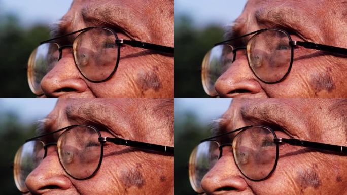 戴眼镜的老人的特写脸在阳光下向远处望去。愿景与老年人观念