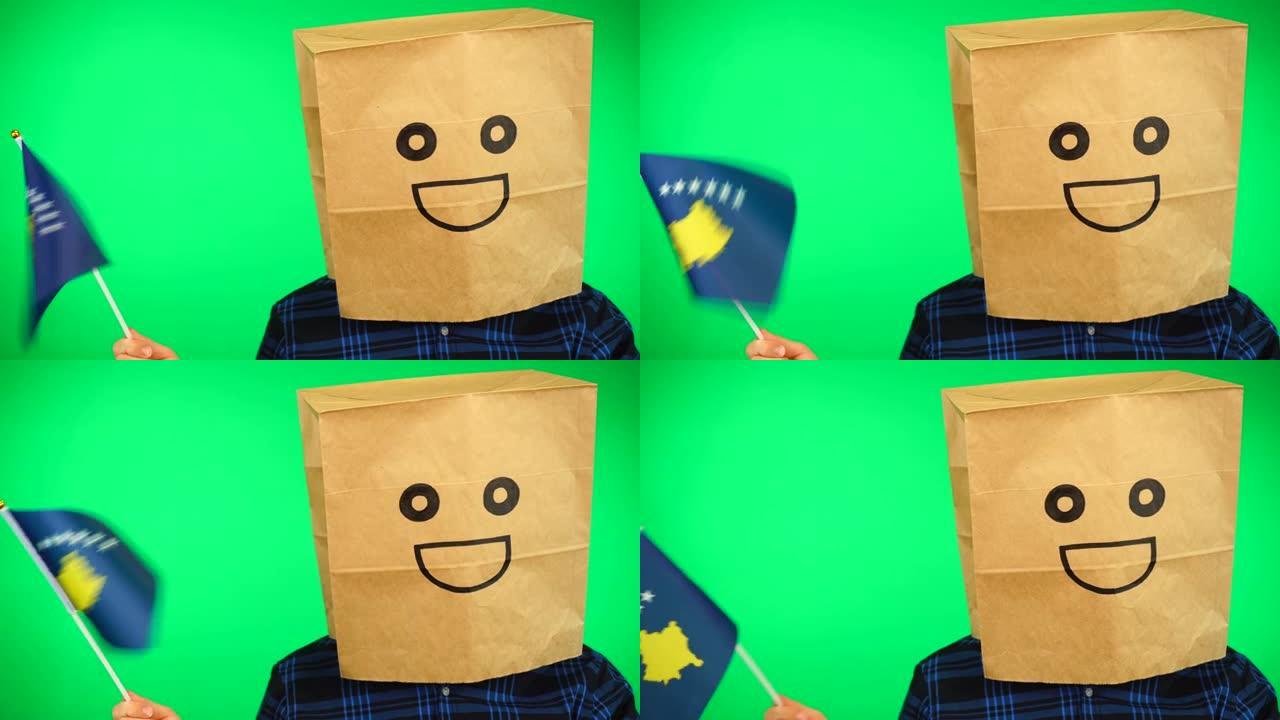 人头戴纸袋的男子肖像，在绿色背景下挥舞科索沃国旗，面带微笑。