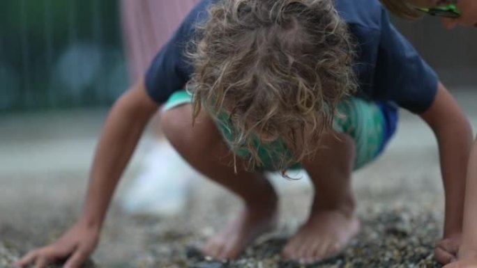 小男孩在海滩或公园寻找岩石