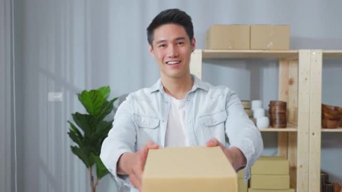亚洲帅哥向店内顾客递包裹的肖像。有吸引力的商业男性在仓库工作场所将包裹交付并交付给客户，并微笑着看着