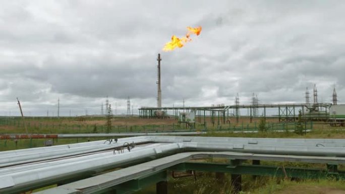 石油精炼厂工业的天然气火炬。前景中的油管。