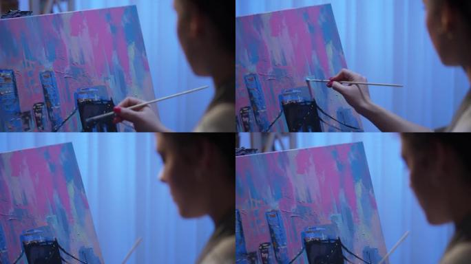 从创意工作室的画布上艺术家绘画的背面看。年轻女子用画笔和调色板上的油画创作绘画。建筑物关闭的城市。慢