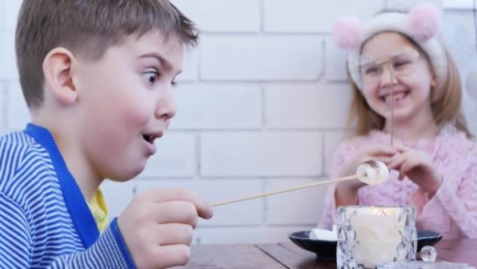 男孩和女孩的青少年在家里野餐，用蜡烛烤棉花糖