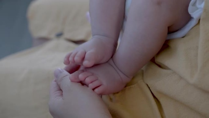 一个2个月大的亚洲新生男孩的脚在母亲的腿上的4k特写镜头，由母亲的手严密保护。
