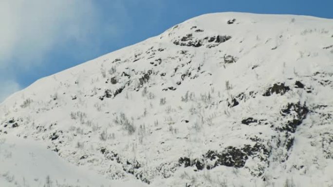 积雪覆盖着树木和岩石的山坡